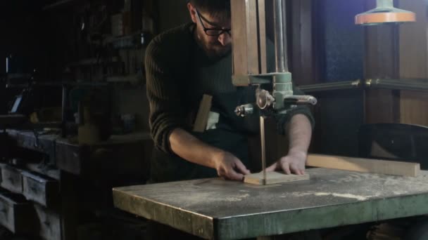 Total field on a carpenter who cuts a piece of wood with a band saw — Stock Video