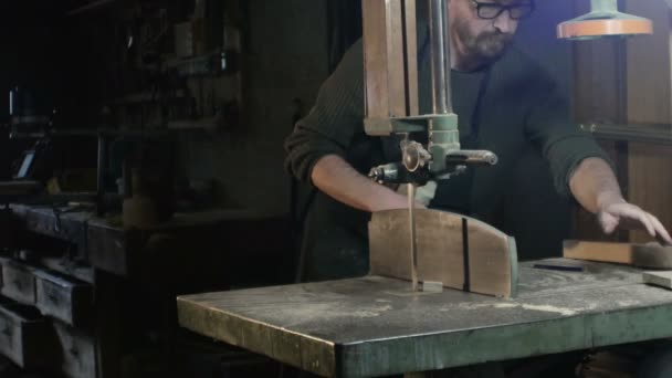 Total field on a carpenter who cuts a piece of wood with a band saw — Stock Video