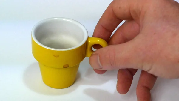 Желтая чашка кофе и рука — стоковое фото