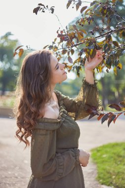 Bir kızın portresi ağaç dalları taşıyordu, yazın aydınlık bir günde, arka planda. Sığ bir alan derinliğinde.