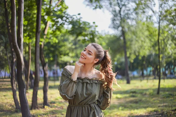 緑のドレスで幸せな若い女の子の肖像画 美しい髪 晴れた日に夏の緑の公園を歩く — ストック写真