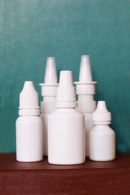 Burun spreyi yeşil arka plana beyaz şişeler düşürür.