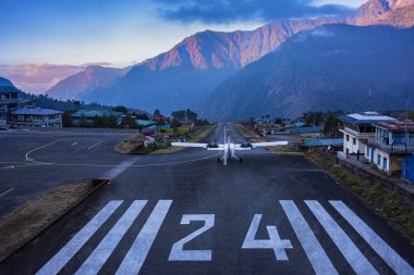 Lukla, NEPAL - December 2, 2019: Lukla airport. In the frame of the airport runway and taking off the plane. Nepal. Everest trekking. clipart