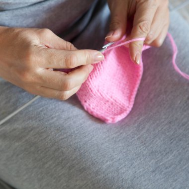 Bir kadın konuşmacı ile pembe bir tuval dokuma kumaşlar. Eller yakın çekim.