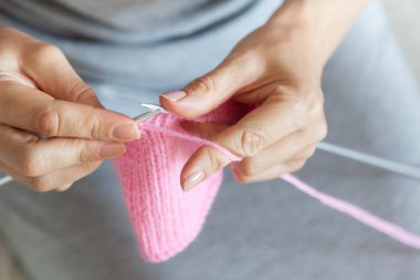 Bir kadın konuşmacı ile pembe bir tuval dokuma kumaşlar. Eller yakın çekim.