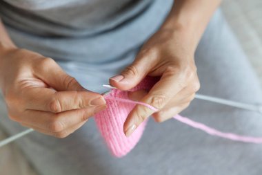 Bir kadın konuşmacı ile pembe bir tuval dokuma kumaşlar. Eller yakın çekim.