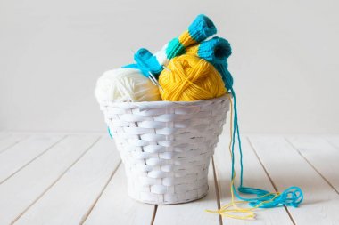 Yün iplik bobinleri ve tangles beyaz sepet içinde. Yapılan bir tablo