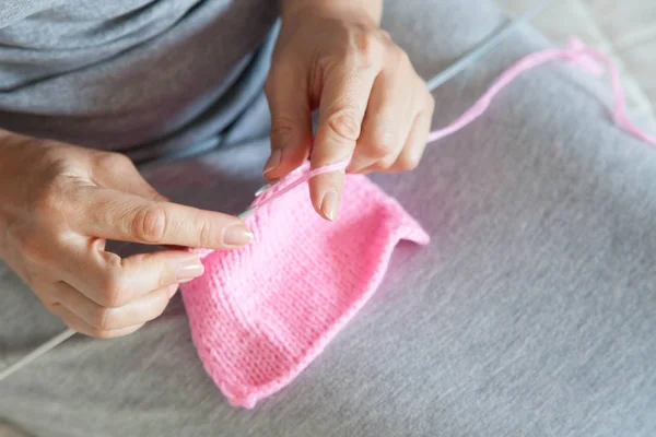 Una donna lavora una tela rosa con i raggi. Mani in primo piano . — Foto Stock