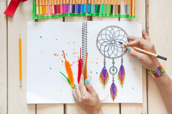 stock image A girl draws a dream catcher with colored markers.