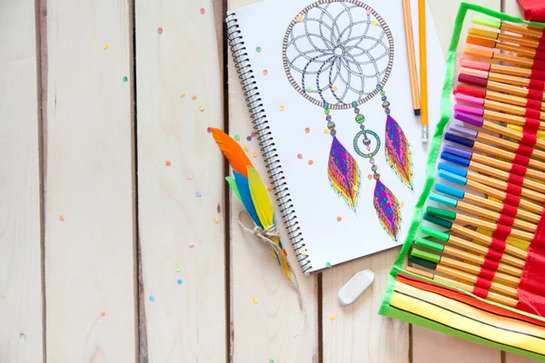 Uma menina desenha um apanhador de sonhos com marcadores coloridos . — Fotografia de Stock