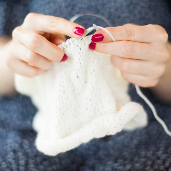 Une femme tricote une toile blanche avec des rayons. Gros plan des mains . — Photo