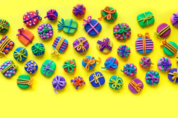 Many small gifts from plasticine. Yellow background. — Stock Photo, Image
