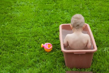 Yeşil çimenlerin üzerinde banyoda küçük çocuk yıkar. 4-5 / çocuk