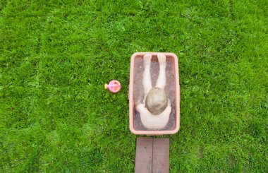 Yeşil çimenlerin üzerinde banyoda küçük çocuk yıkar. 4-5 / çocuk