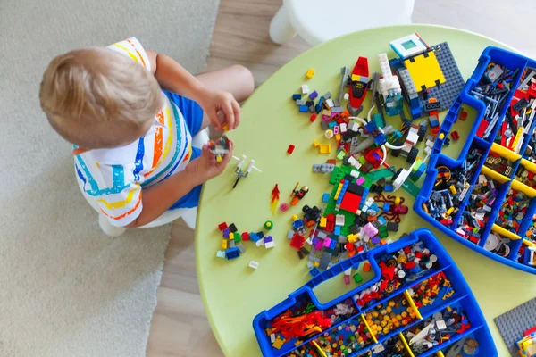 Pequeño niño rubio jugando con un montón de bloques de plástico de colores — Foto de Stock