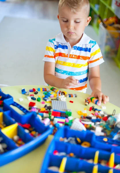 Pequeño niño rubio jugando con un montón de bloques de plástico de colores — Foto de Stock