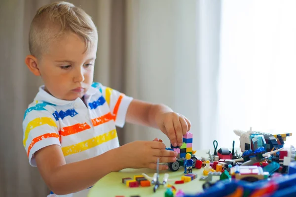 Malý blonďatý kluk hrát se spoustou barevných plastových bloku — Stock fotografie