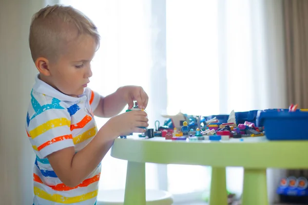 Pequeño niño rubio jugando con un montón de bloques de plástico de colores — Foto de Stock