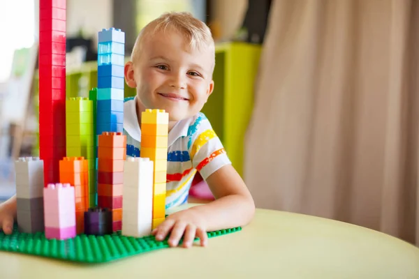 Blond kind jongetje spelen met veel kleurrijke plastic blok — Stockfoto