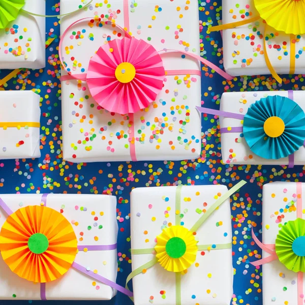 Weiße Geschenke. glänzende Satinbänder. bunte Rosetten wie Dekoration — Stockfoto