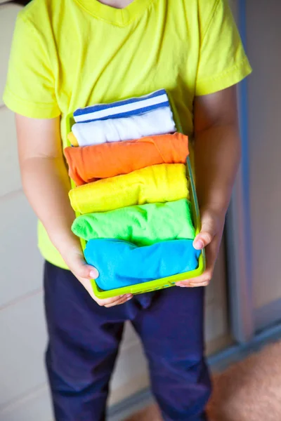 Het kind houdt zijn dingen. De jongen zet de T-shirts in een drawe — Stockfoto