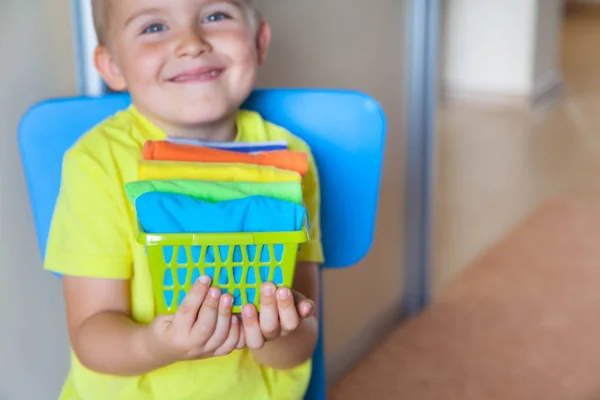 A criança guarda as suas coisas. O rapaz põe as t-shirts num ralo. — Fotografia de Stock
