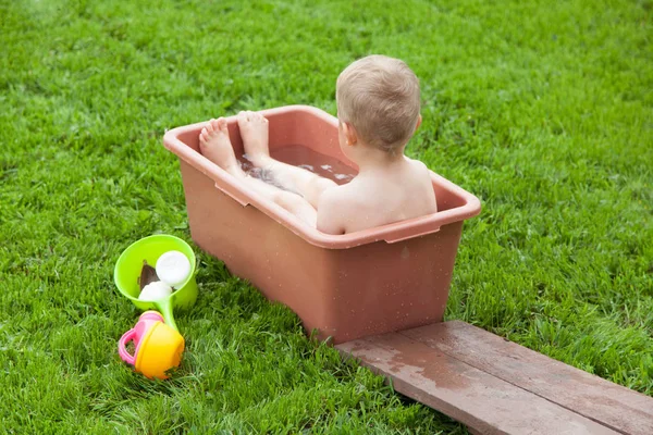 Bambino si lava in bagno sull'erba verde. Ragazzo 4-5 anni — Foto Stock