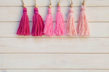 Pembe püsküllü. Arka plan beyaz ahşap.