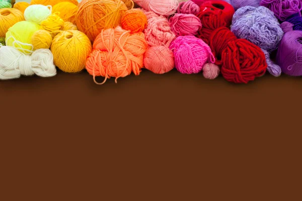 Colorful yarn stacked in a series of colors. Background brown. B — Stock Photo, Image