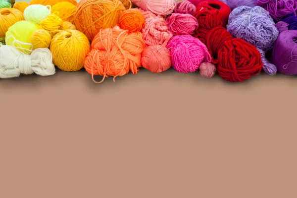 Colorful yarn stacked in a series of colors. Background brown. B