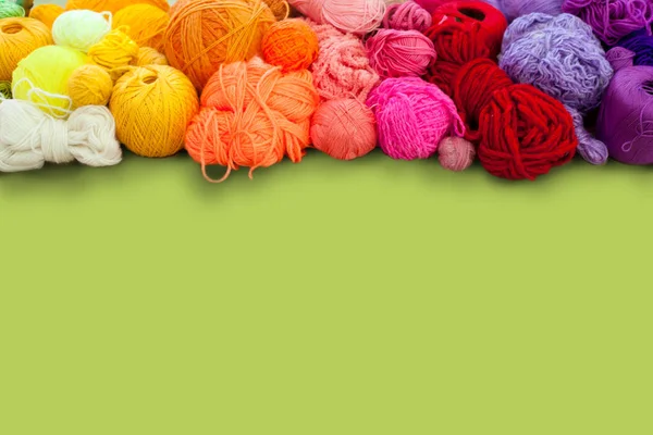 Colorful yarn stacked in a series of colors. Background green. B — Stock Photo, Image