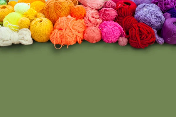 Colorful yarn stacked in a series of colors. Background green. B — Stock Photo, Image