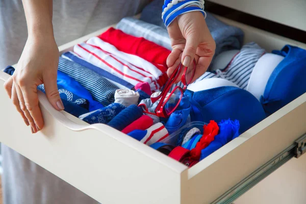 Düzgünce katlanmış giysileri Çekmeceli aksesuarları ile. Mari