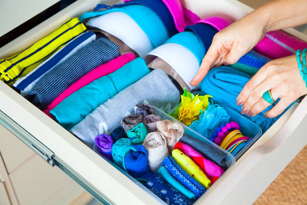 аккуратно сложенная одежда с аксессуарами в комоде
