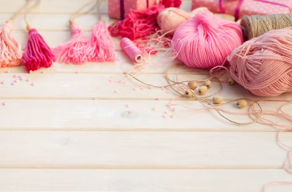 Pink tassels. Background of white wood. Women's handicrafts. The — Stock Photo, Image