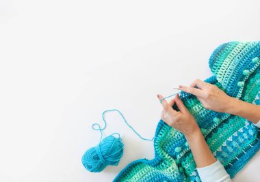 Kadınların elleri büyüktür. Kadın örgü örüyor. Yeşil iplik, turkuaz