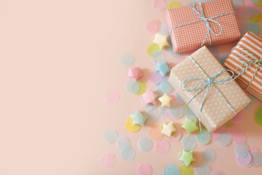 Hediye kutuları ve pastel renkli konfeti. Pembe arkaplan.