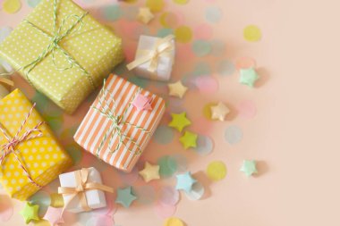 Hediye kutuları ve pastel renkli konfeti. Pembe arkaplan.