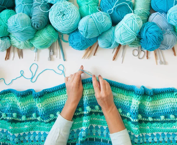 Kadınların elleri büyüktür. Kadın örgü örüyor. Yeşil iplik, turkuaz