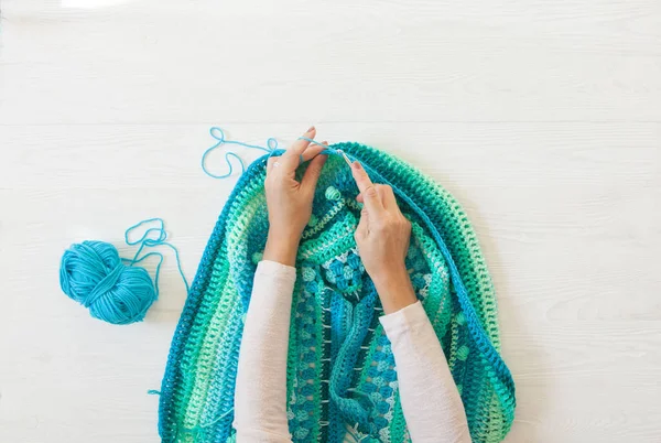 Women's hands are large. Woman crochets. Yarn of green, turquois — Stock Photo, Image