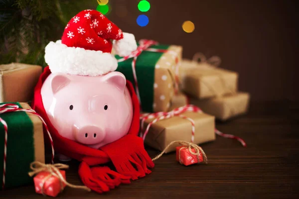 Свинка в рождественской шляпе Санта Клауса. Подарочные коробки, ели отруби — стоковое фото