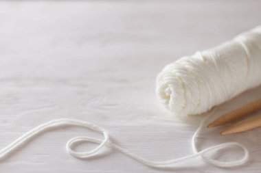 Örgü iğneleri, beyaz iplik, ahşap arka plan.