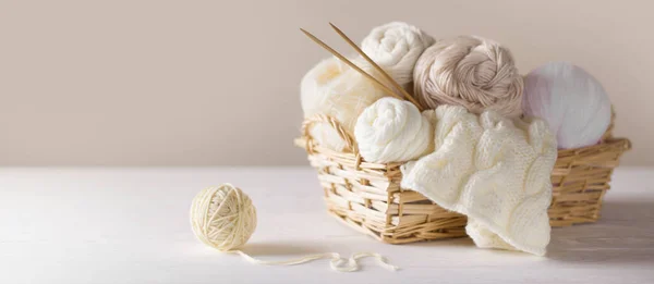 Fio branco e bege para tricotar em uma cesta. Agulhas de tricô . — Fotografia de Stock