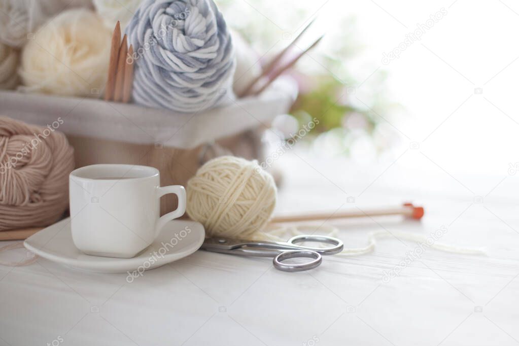 White and beige yarn for knitting in a basket. Knitting needles,