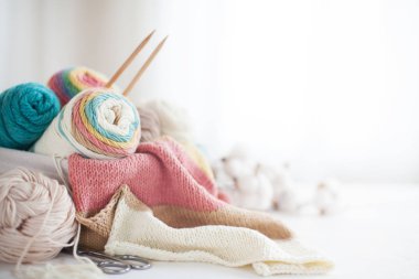 Beyaz torbaya pastel renkte yün ve örgü iğneleri örüyorum.