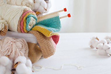 Beyaz torbaya pastel renkte yün ve örgü iğneleri örüyorum.