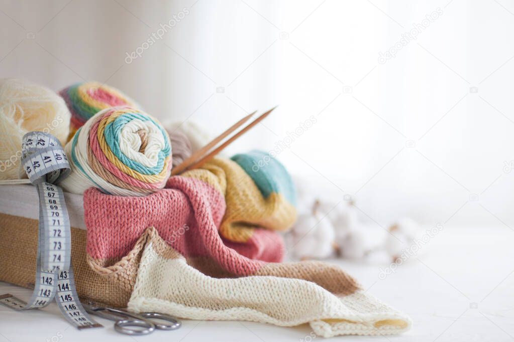 Knitting wool and knitting needles in pastel colors on white bac