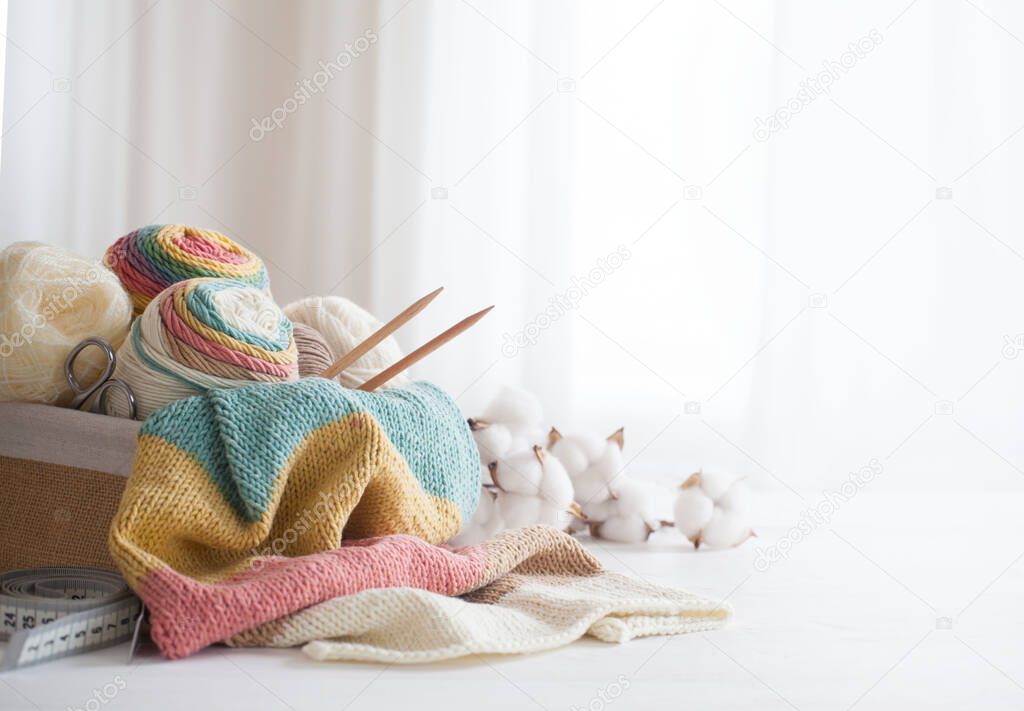 Knitting wool and knitting needles in pastel colors on white bac
