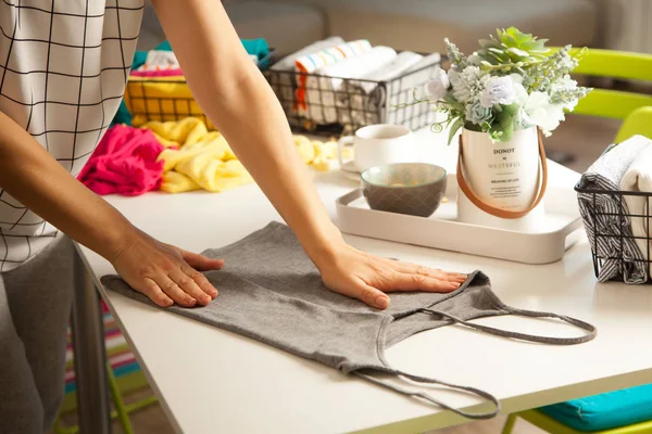 A woman folds her clothes and puts them in metal black baskets a — 스톡 사진