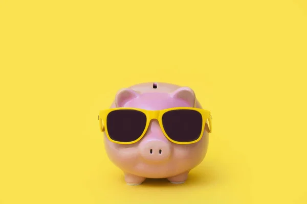 A pink piggy bank in sun glasses at a party. Yellow background. — Stok fotoğraf